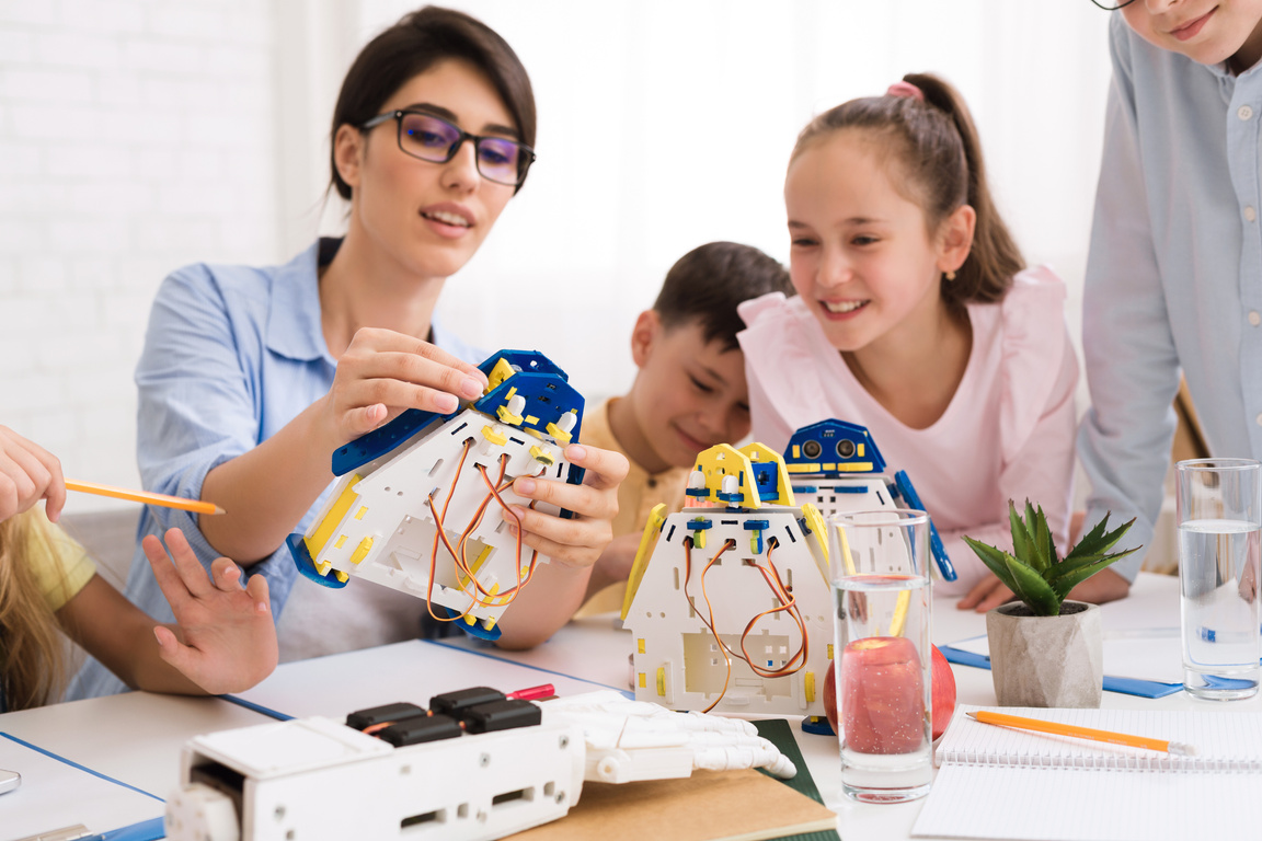 Stem education. Kids constructing robots with teacher